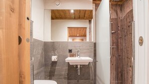 A modern bathroom with a wooden door, a white sink, and a toilet. - 1214 Piz Buin Schima Drosa (Gaschurn)