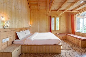 Une chambre dans une cabane en bois, avec un lit, un banc et une fenêtre avec des rideaux.