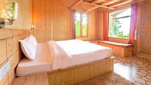 A wooden cabin bedroom with a bed, bench, and windows.