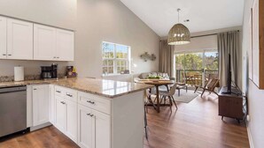 A modern kitchen with white cabinets, a granite countertop, and a dining area with a table and chairs. - Whiskey's Hillside Retreat -holiday Hills Branson - Golf Resort (Branson)
