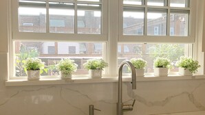 Eine Küche mit weißem Marmorarbeitsplatz, einem Spülbecken und einem Fenster mit vielen Fensterscheiben.
