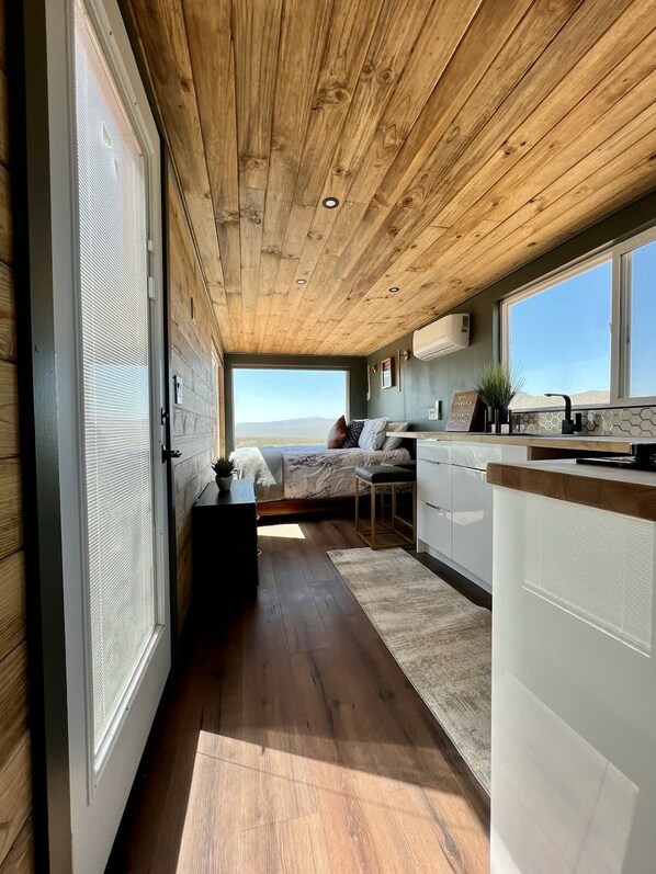 Une chambre à coucher de taille modeste, comprenant un lit, une table de chevet et offrant une vue sur le paysage grâce à une grande fenêtre.