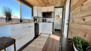 Une cuisine moderne avec des armoires blanches, un plafond en bois et une vue sur l’extérieur.