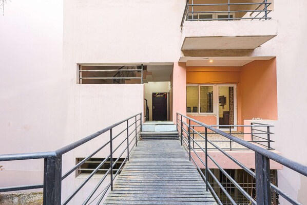 Escadaria que leva a uma entrada de apartamento, com corrimão de metal e porta com painel de vidro.