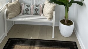Un banc blanc avec des coussins à motifs, un élément décoratif mural et une plante en pot.