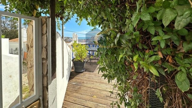 A wooden deck leading to a house with a stone wall and a view of a mountain. - T1 Sunset View (Albufeira)