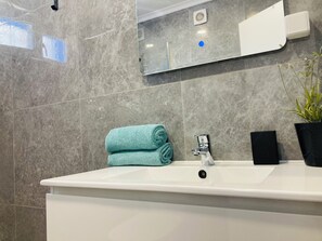 A bathroom with a white sink, a mirror, a towel, a potted plant, and a black box. - T1 Sunset View (Albufeira)