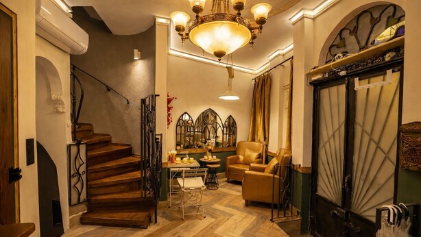 A staircase leading to a room with a chandelier, a chair, and a mirror. - The House Company (Istanbul)