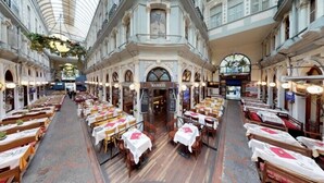 A spacious indoor dining area with multiple tables and chairs, a central archway, and a high ceiling with a skylight. - The House Company (Istanbul)