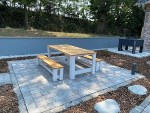 A picnic table with benches in a landscaped garden area.