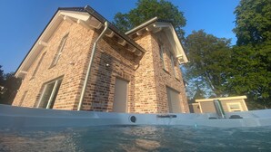 Ein Backsteinhaus mit Garagentor, Schwimmbecken und blauem Himmel.