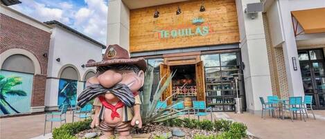 A restaurant named "Tequilas" with a large outdoor seating area and a decorative statue in front.