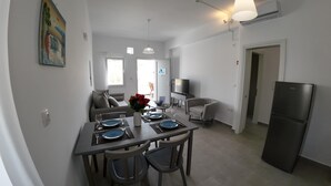 A modern kitchen with a dining area, a TV, and a refrigerator. - Air house          . (Mykonos)