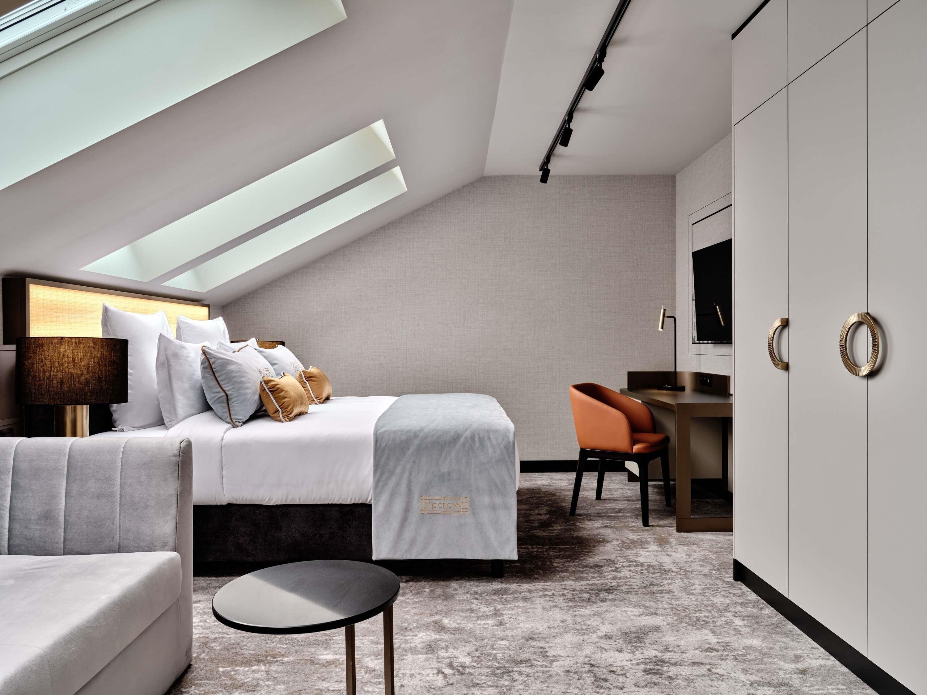 Ein modernes Hotelzimmer mit Bett, Schreibtisch, Stuhl und Fernseher.
