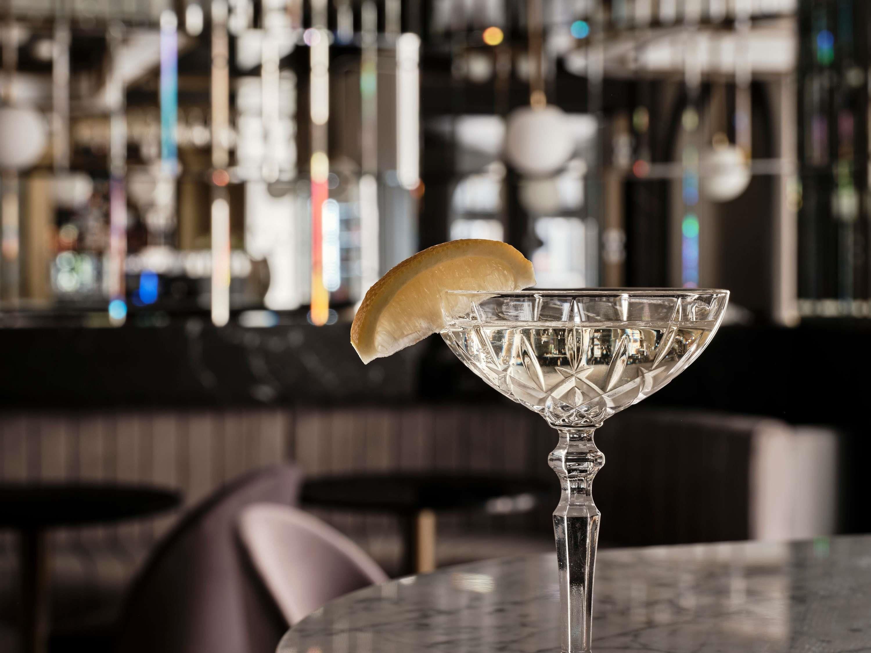 A bar setting with a clear glass martini glass on a marble table.