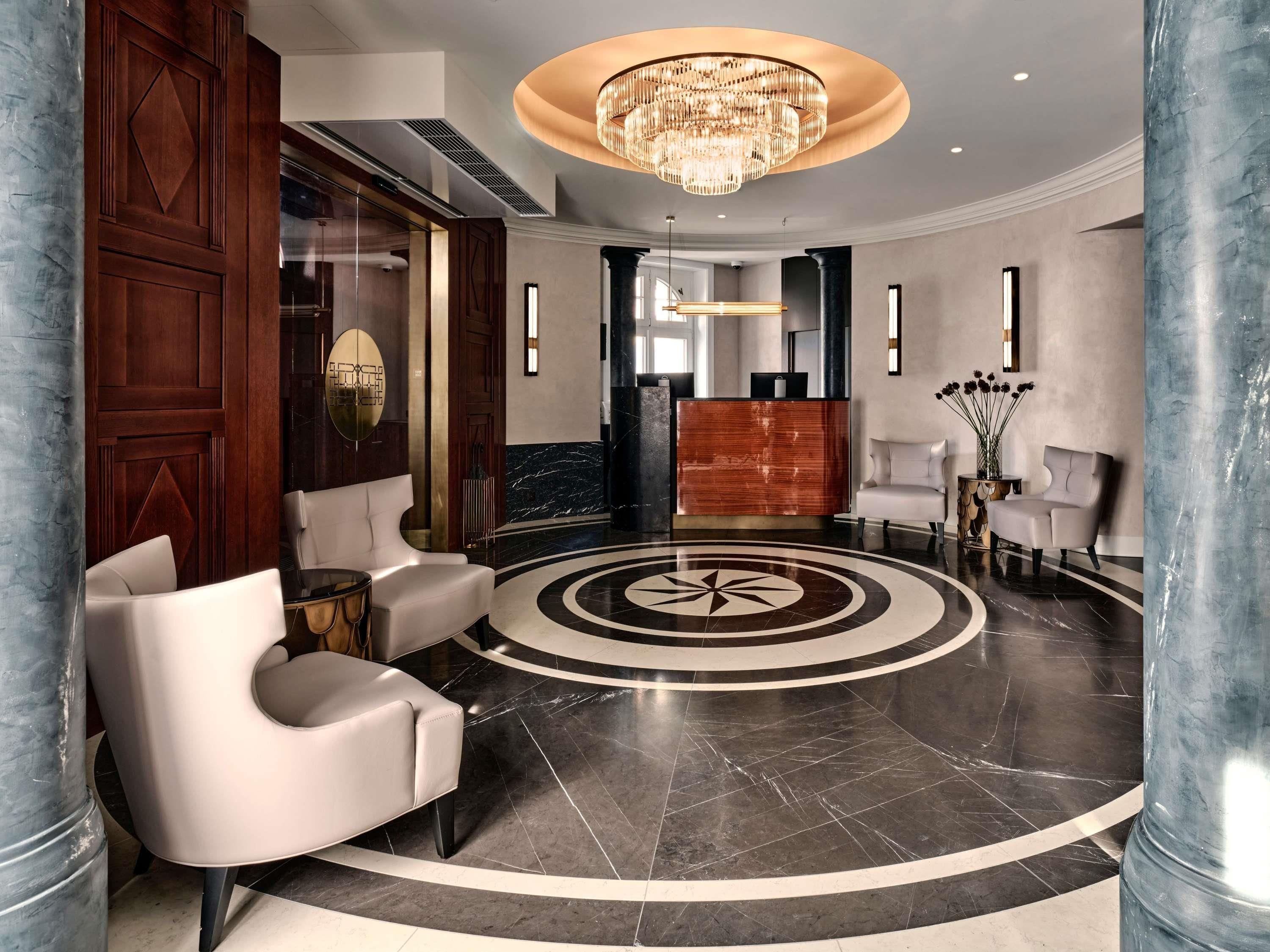 A lobby with a reception desk, seating area, and a large chandelier.