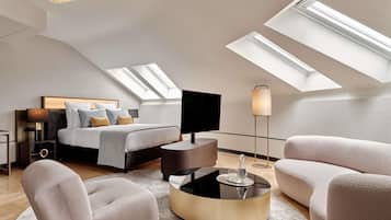 A modern bedroom with a bed, a TV, a lamp, a round coffee table, and a sofa.