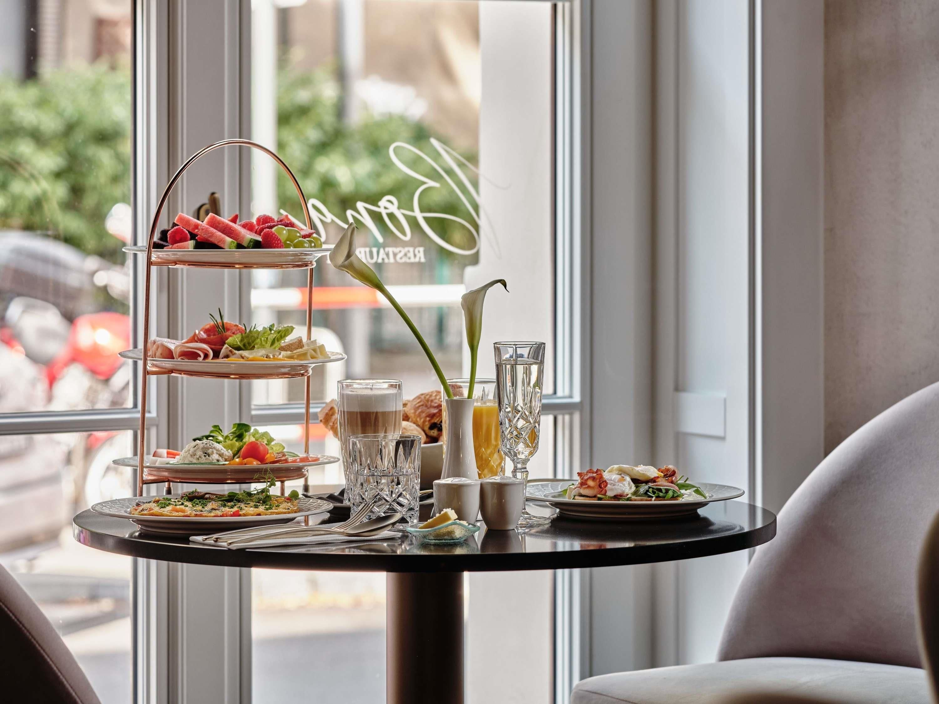 A table with a three-tiered dessert stand, a glass of juice, and a coffee cup.