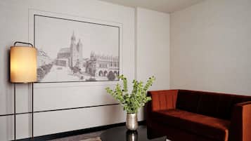 A modern room with a framed cityscape artwork, a round black coffee table with a gold base, a red velvet sofa, and a floor lamp.