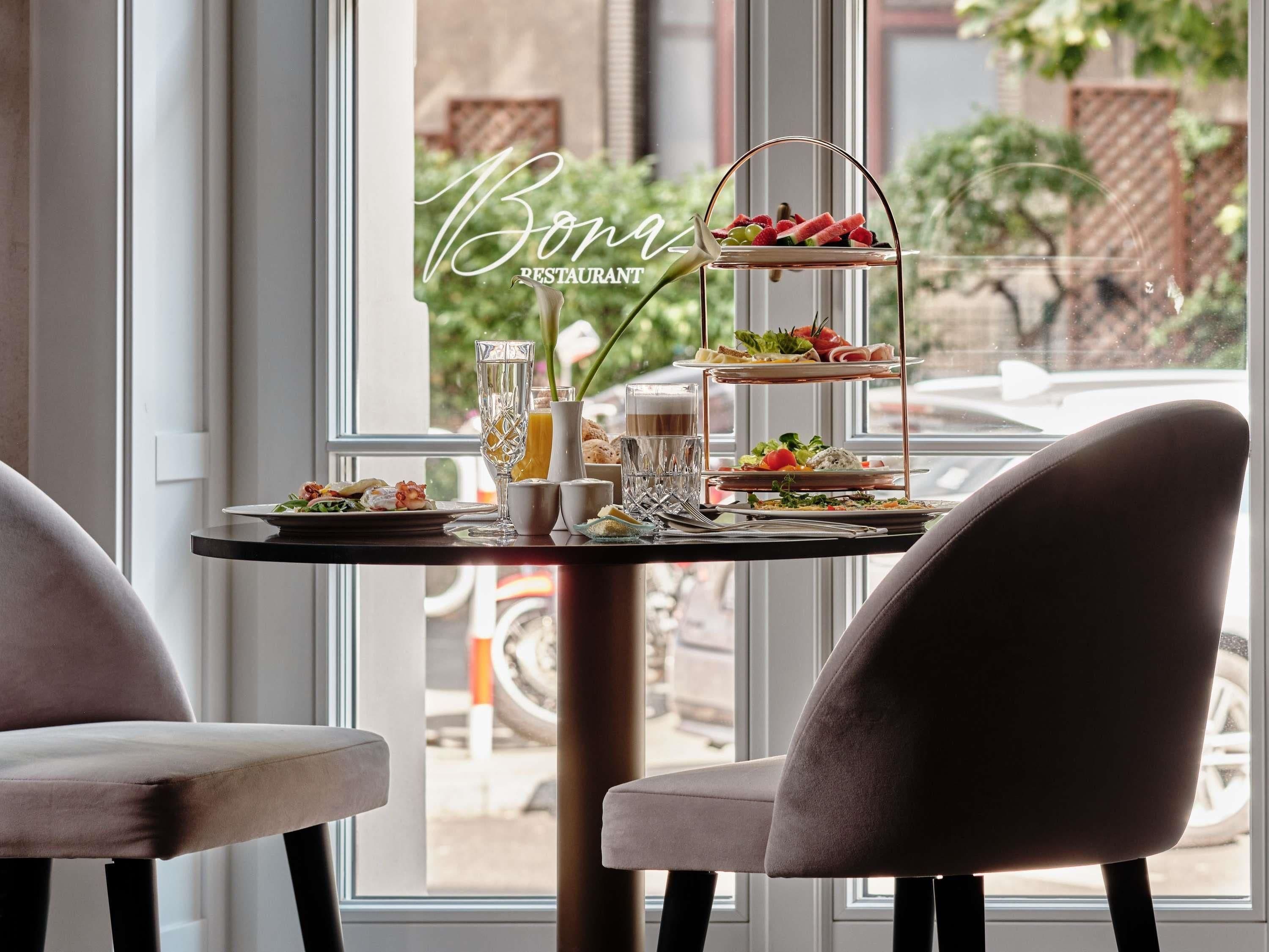 A restaurant setting with a tiered dessert display, a glass of water, and a plate of food.