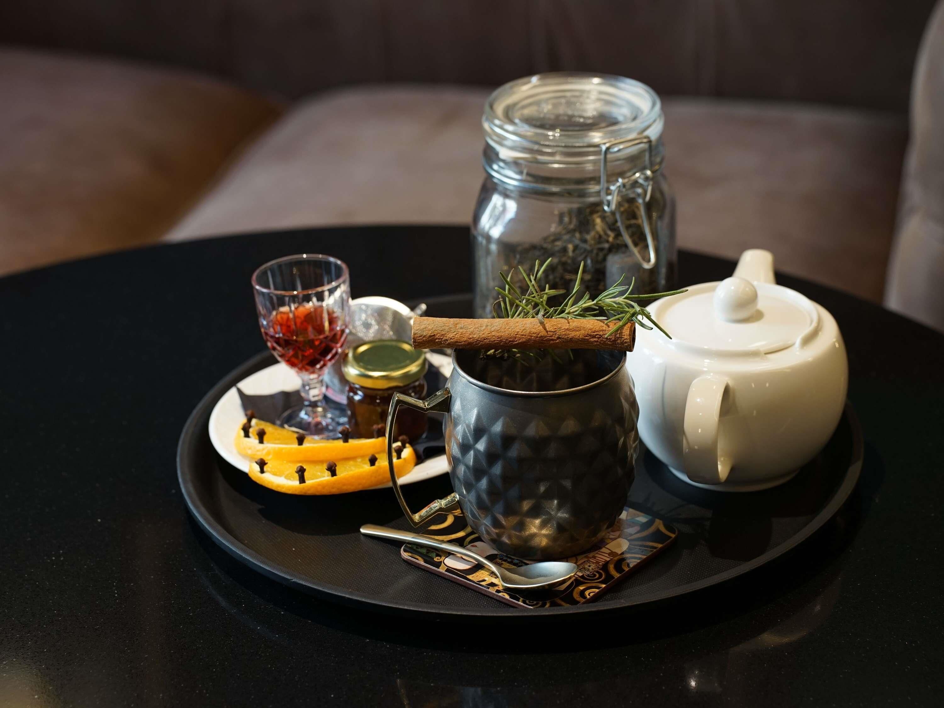 Een dienblad met een theepot, een glas, een pot en een kaneelstokje.