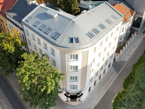 Un bâtiment d’angle doté d’un toit incurvé, de nombreuses fenêtres et d’une entrée centrale surmontée d’un balcon.
