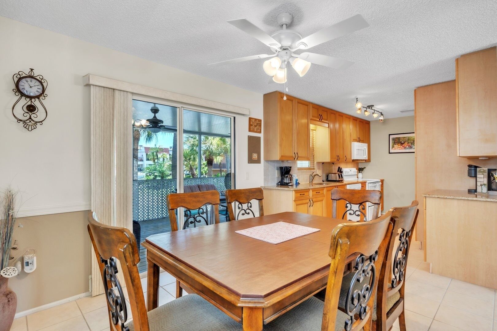 A dining area with a wooden table and chairs, a ceiling fan, and a kitchen with wooden cabinets.