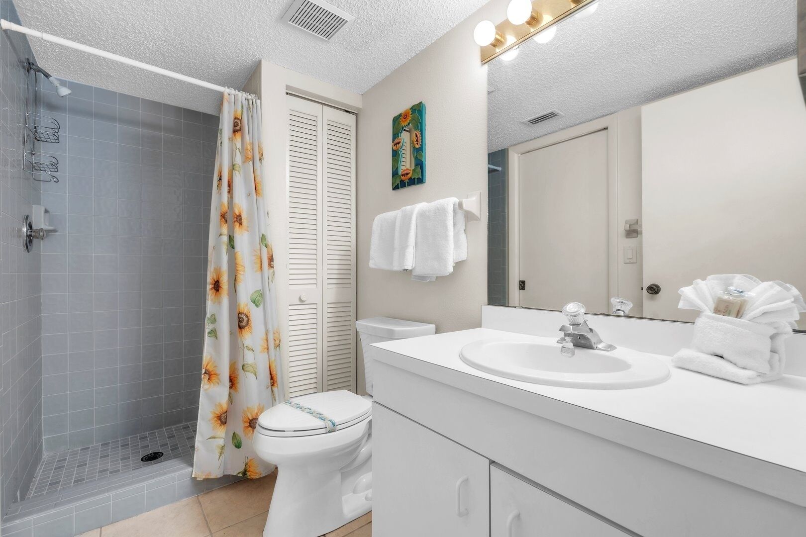 A bathroom with a shower, toilet, sink, and a mirror.