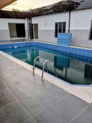 A swimming pool with a tiled edge, a metal ladder, and a tiled wall with a blue pattern. - H31 Royal Classic Apartments  (Lagos)