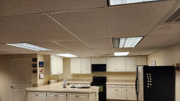 A kitchen with white cabinets, a black refrigerator, and a central island.