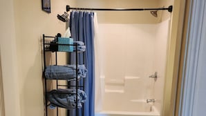A bathroom with a shower, toilet, and a towel rack with towels.