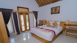 A neatly arranged bedroom with a wooden bed, a nightstand, and a painting on the wall. - Kubuyang Cottage (Penida Island)