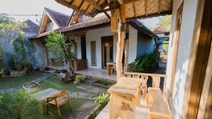 A traditional house with a thatched roof, wooden furniture, and a garden with a stone pathway. - Kubuyang Cottage (Penida Island)