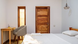 Un dormitorio con una cama, una silla, una puerta de madera y una mesita.