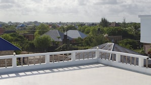Terraza en la azotea con barandilla blanca, con vistas a edificios residenciales y zonas verdes.