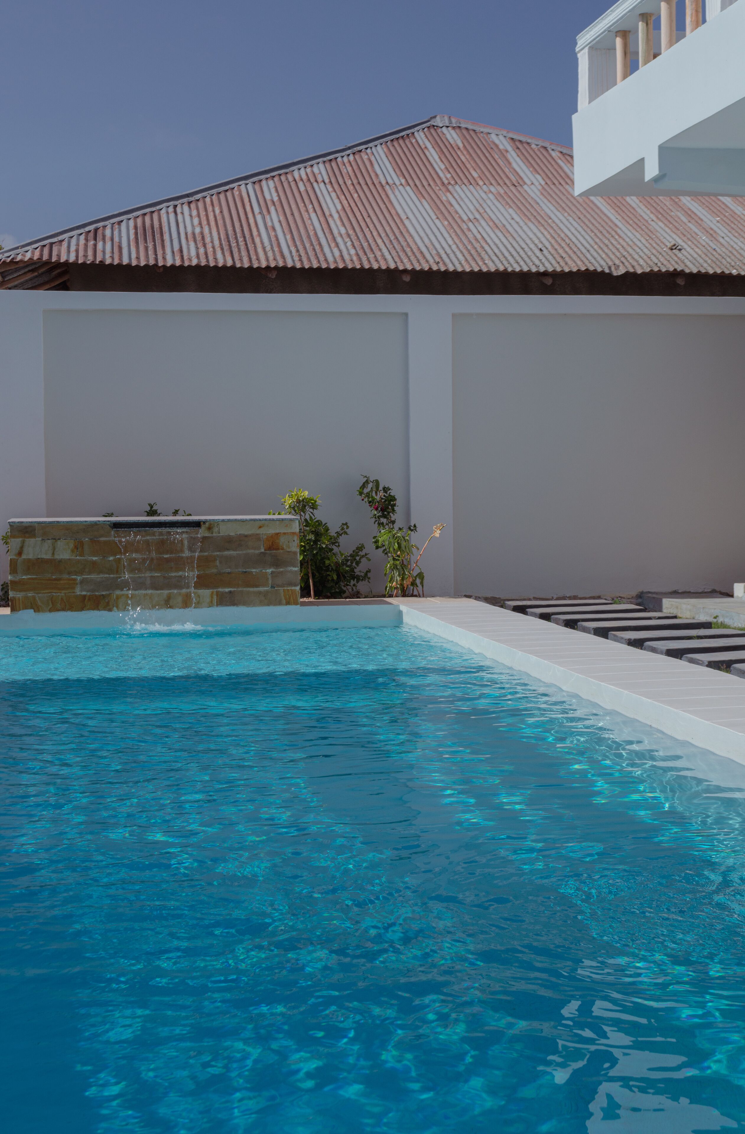 A swimming pool with a stone wall and a metal roof.