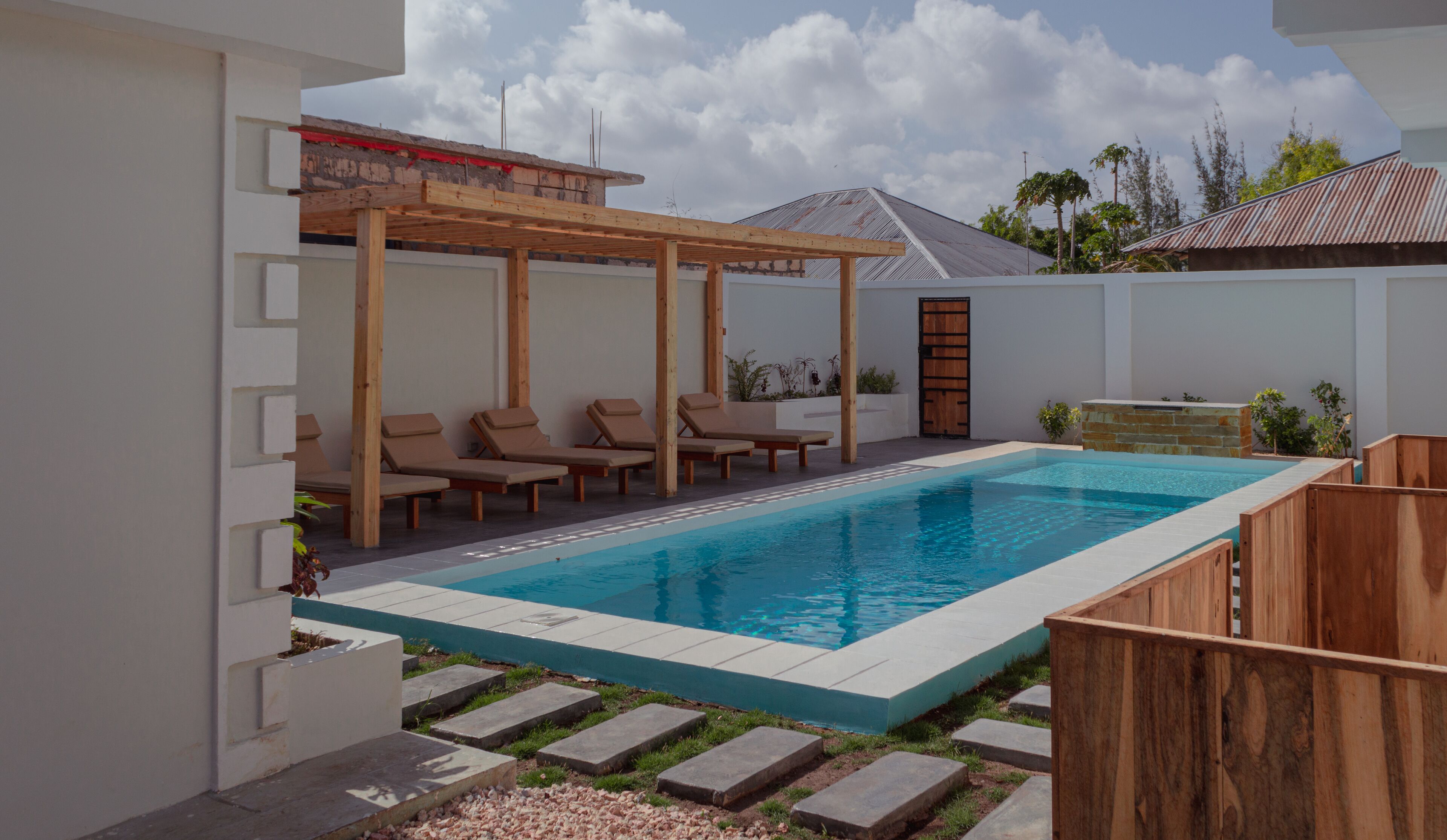 Ein rechteckiger Swimmingpool mit Holzdeck und Liegestühlen.