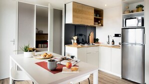 Una cocina moderna con armarios blancos, un refrigerador de acero inoxidable y una encimera de madera.