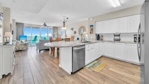 Una cocina moderna con armarios blancos, una isla central y vistas al exterior.