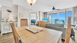 Una habitación bien iluminada con una mesa de comedor, sillas, un sofá y vistas al mar a través de amplios ventanales.