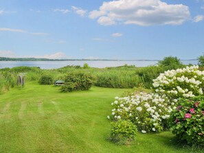 A grassy area with a view of a lake and a boat dock. - 6 Person Holiday Home in Jaegerspris (Jægerspris)