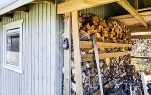 A wooden structure with a window and a pile of firewood. - 6 Person Holiday Home in Jaegerspris (Jægerspris)