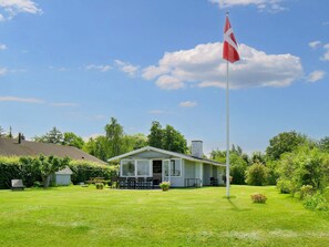 A house with a flagpole, a lawn, and a small shed. - 6 Person Holiday Home in Jaegerspris (Jægerspris)