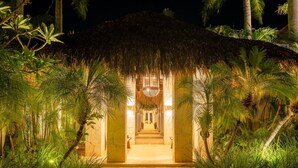 A pathway leading to a thatched-roof structure surrounded by lush greenery.