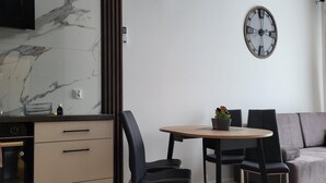 Eine moderne Küche mit Marmorfliesenspiegel, Einbauofen und Essbereich mit rundem Tisch und vier Stühlen.