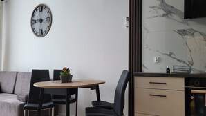 A modern kitchen with a marble backsplash, a round dining table with chairs, and a built-in oven. - A comfortable apartment close to the seaside beach (Gaski)
