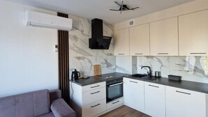 A modern kitchen with white cabinets, a built-in oven, and a grey countertop. - A comfortable apartment close to the seaside beach (Gaski)