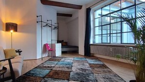 Una sala de estar moderna con un ventanal grande, un sofá, una mesita de centro y una lámpara de pie.