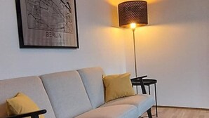 Una sala de estar moderna con un sofá de tonos claros, una obra de arte con un mapa, una lámpara de pie y una alfombra estampada.