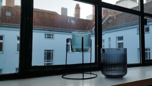 Una ventana con vista a un edificio de techos rojos y paredes blancas.
